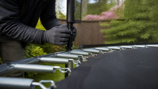 Iemand inspecteert de veiligheidsnet-bevestiging en springmat van een trampoline in de lente