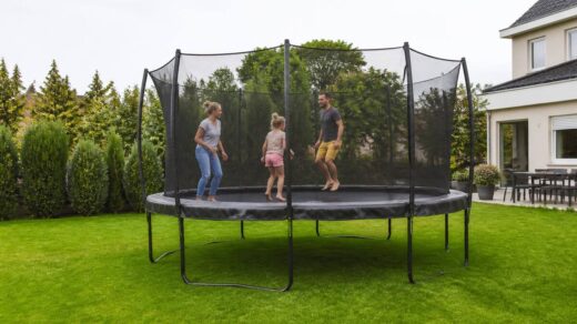 Trampoline met veiligheidsnet en randkussen in een tuin, klaar voor gebruik